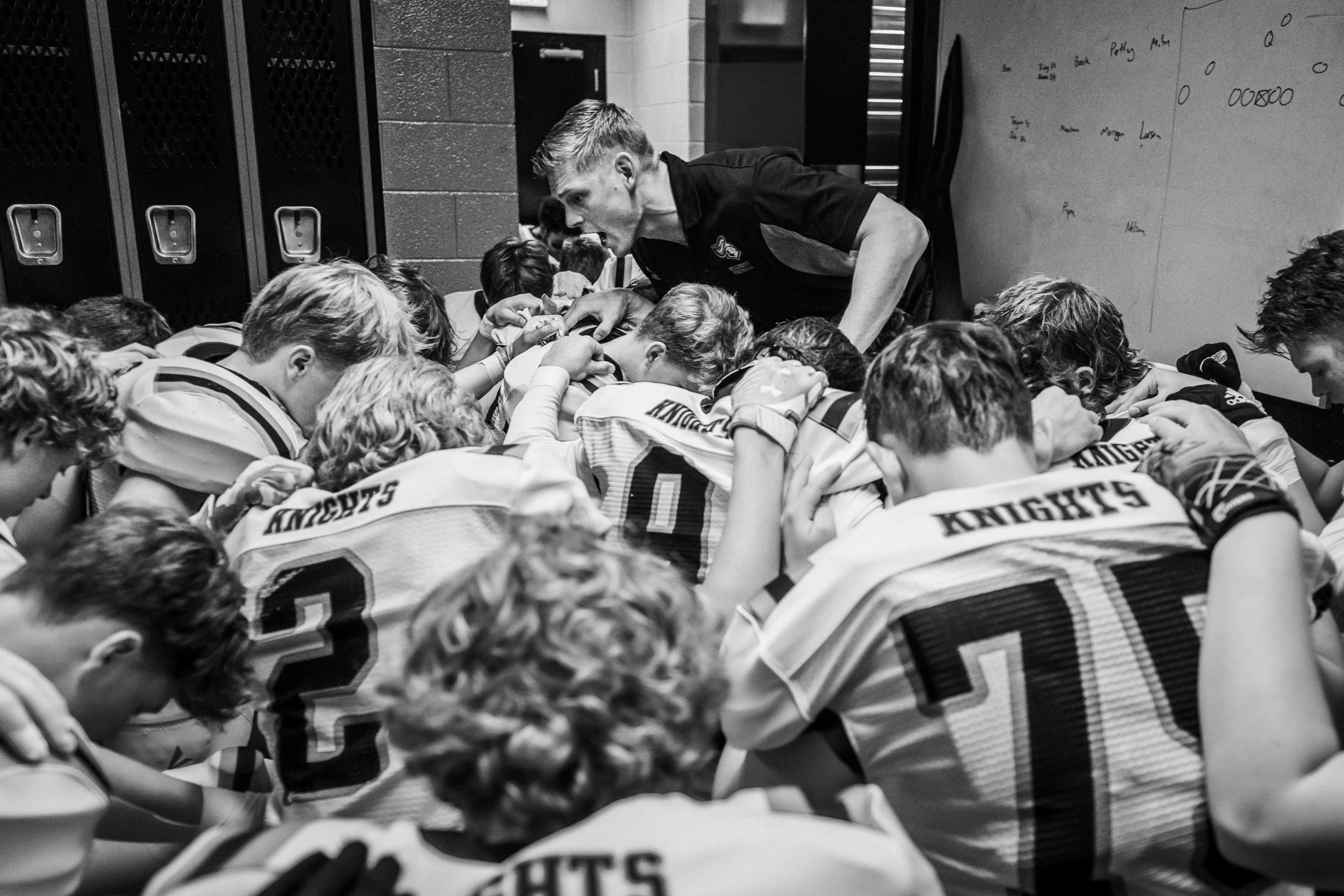 Football team and coach in a pre-game locker room huddle